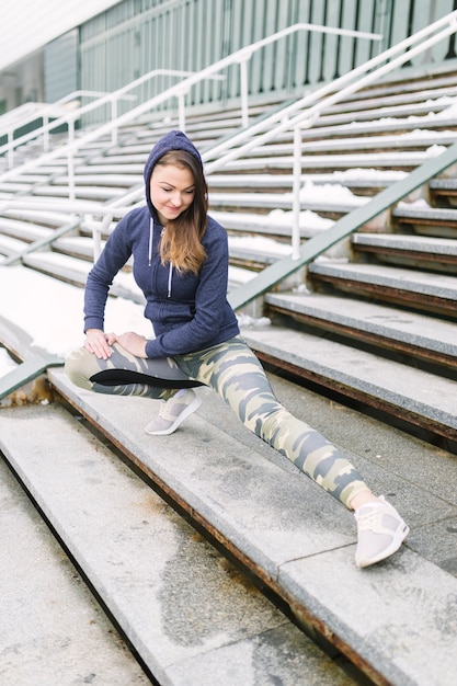 Photo gratuite belle femme qui s'étend des jambes dans les escaliers