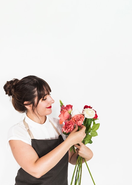 Belle femme regardant un bouquet de fleurs sur fond blanc