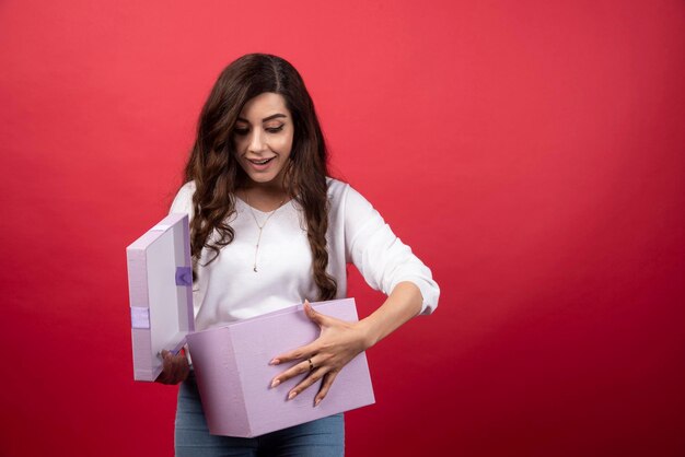 Belle femme regardant à l'intérieur de la boîte présente violette. photo de haute qualité