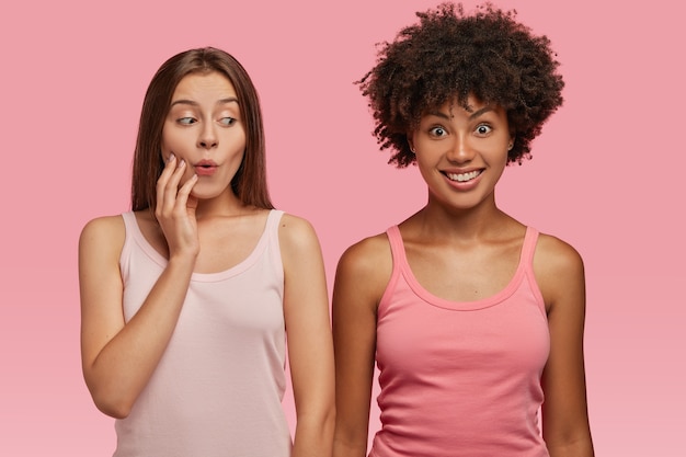 Photo gratuite belle femme regarde étonnamment un ami joyeux à la peau sombre