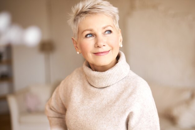 Belle femme à la retraite heureuse portant un pull confortable et une coiffure courte