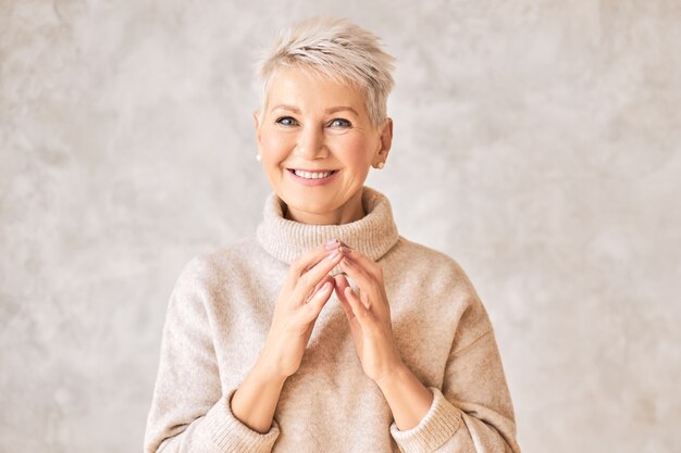 Belle femme à la retraite heureuse portant un pull confortable et une coiffure courte