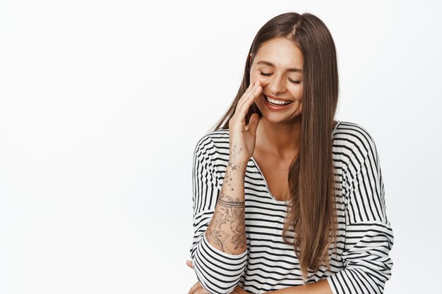 Belle femme riant, expression naturelle, fille s'amusant, réaction à qch drôle, debout sur blanc