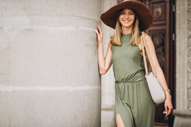 Belle femme en robe et chapeau debout par architecture