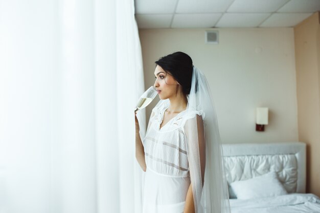 Belle femme en robe de mariée buvant du champagne