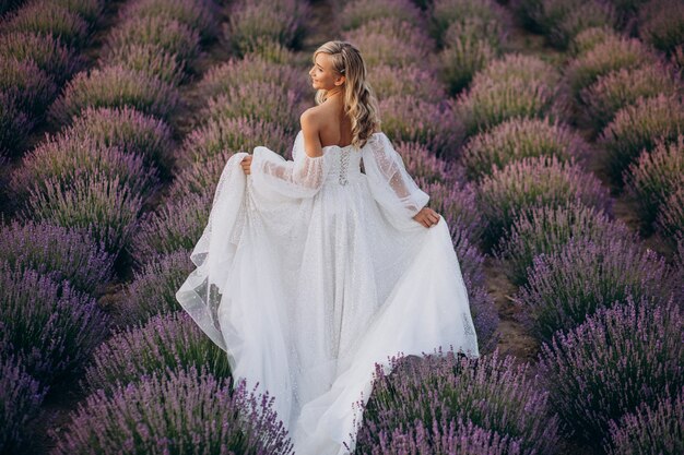 Belle femme en robe de mariée dans le champ de lavande