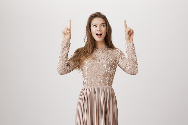 Photo gratuit belle femme en robe de soirée pointant vers le haut