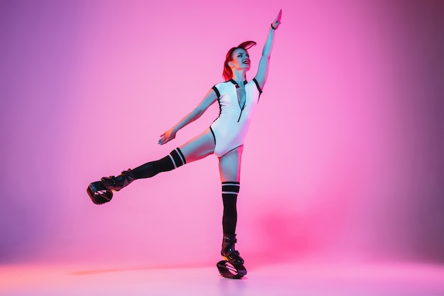 Belle femme rousse dans un vêtement de sport blanc sautant dans un kangoo saute des chaussures