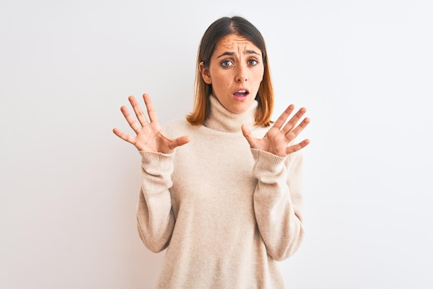 Photo gratuite belle femme rousse portant un pull à col roulé d'hiver sur fond isolé effrayé et terrifié par l'expression de peur geste d'arrêt avec les mains criant sous le choc concept de panique