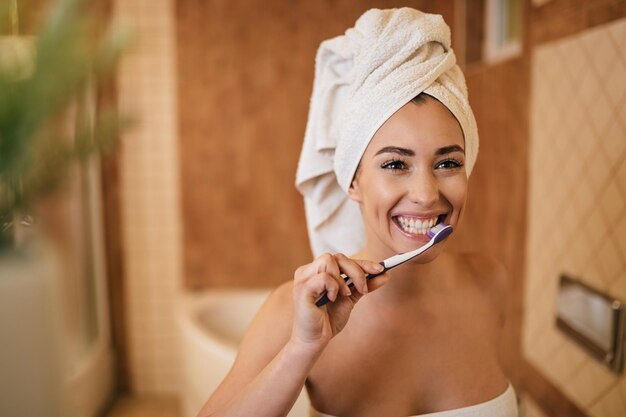 Belle femme se brosser les dents avec une brosse à dents dans la salle de bain