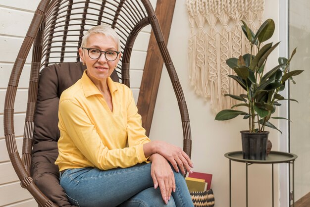 Belle femme senior assise sur une chaise en bois