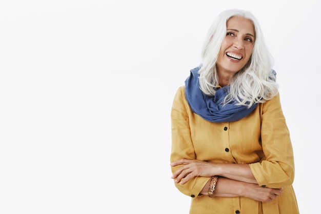 Photo gratuite belle femme senior coquette aux cheveux gris souriant et à la recherche dans le coin supérieur gauche