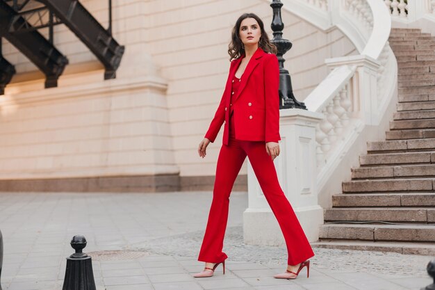 Belle femme sexy de style d'affaires riche en costume rouge marchant dans la rue de la ville, tendance de la mode printemps été