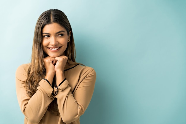 Belle femme souriante avec les mains sur le menton regardant loin sur fond isolé