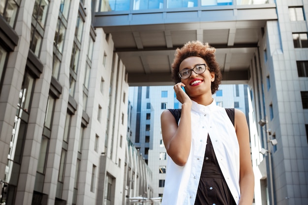 Belle femme souriante parlant au téléphone en descendant la ville