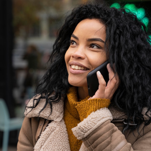 Belle femme souriante parlant au téléphone à l'extérieur