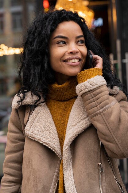 Belle femme souriante parlant au téléphone à l'extérieur