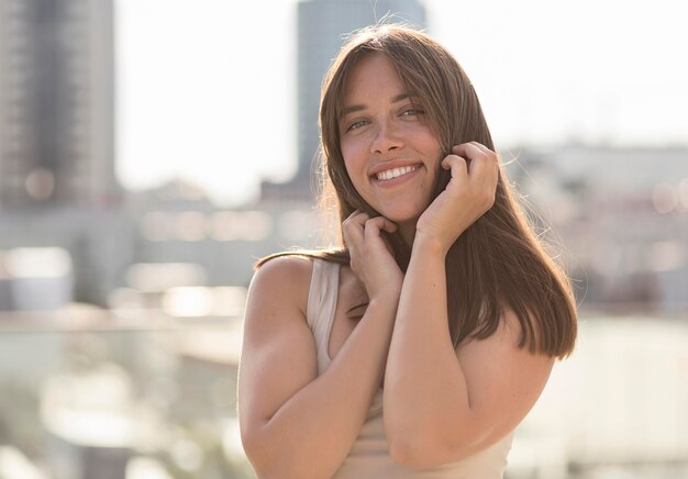 Belle femme souriante posant à l'extérieur