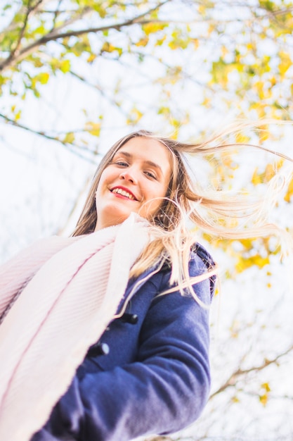 Photo gratuite belle femme souriante regardant d'en haut à la surface du ciel automne