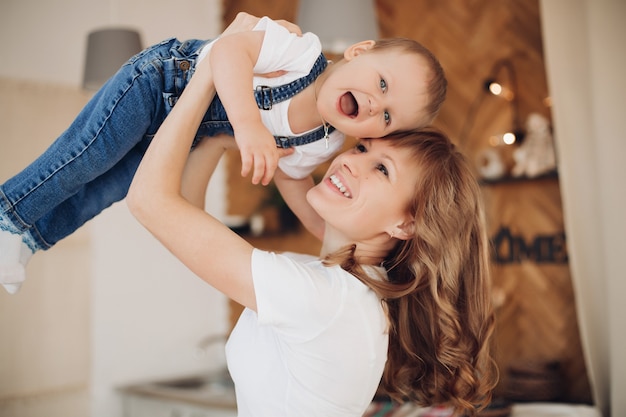 Belle femme souriante et son petit enfant se relaxant à la maison tout en s'amusant. Concept de famille et de maternité