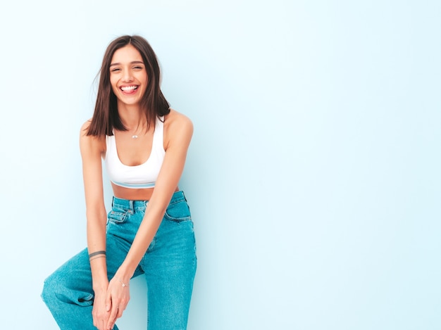 Photo gratuite belle femme souriante vêtue d'une chemise en jersey blanc et d'un jean