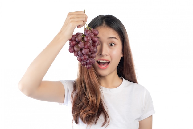 Belle femme avec un sourire heureux, tenant un raisin de la main, isolé sur fond blanc.