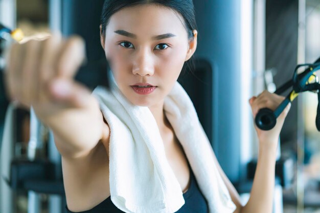 Belle femme sportive asiatique séance d'entraînement avec machine de musculation pour faire de l'exercice en fitness belle femme soulève des haltères lourds tout en s'entraînant dans le fitness