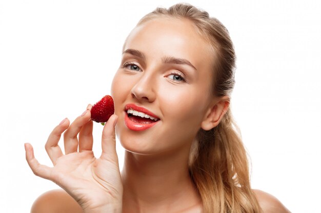 Belle femme sportive posant, mangeant des fraises