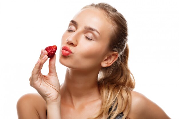 Belle femme sportive posant, mangeant des fraises