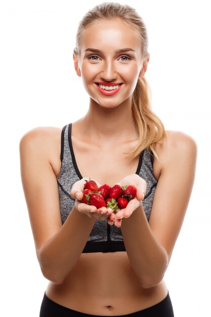 Belle femme sportive posant, tenant des fraises