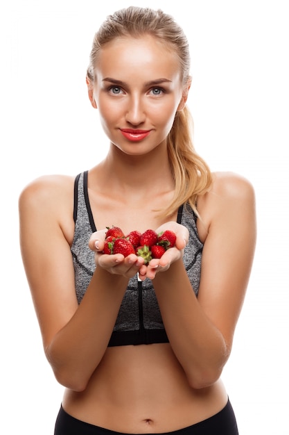 Belle femme sportive posant, tenant des fraises