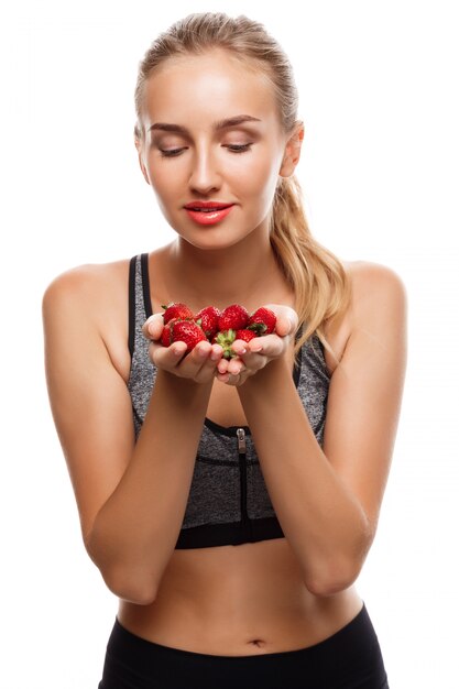 Belle femme sportive posant, tenant des fraises