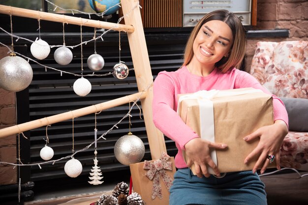 Belle femme tenant une boîte-cadeau à la maison