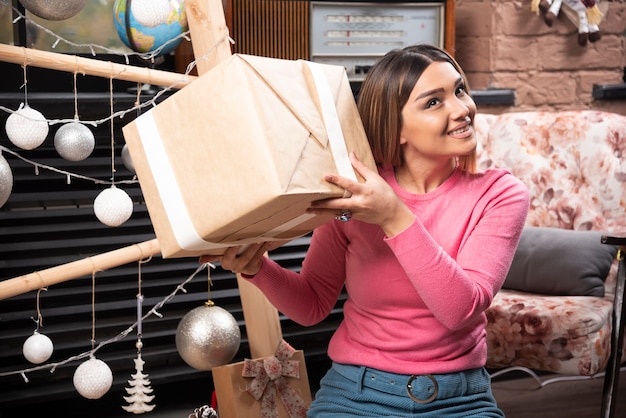 Belle femme tenant une boîte-cadeau à la maison