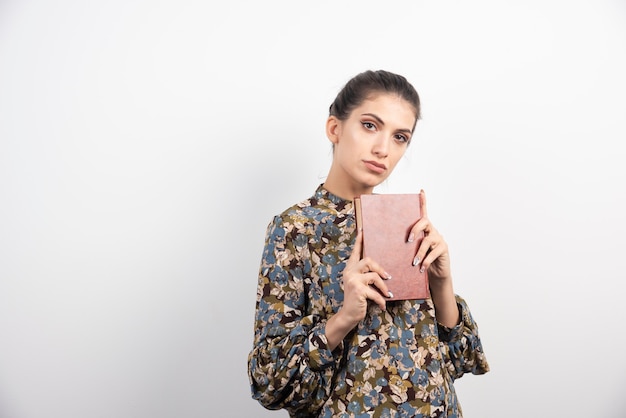 Belle femme tenant le livre étroitement.