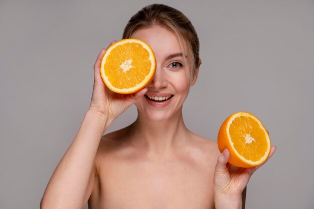 Belle femme tenant orange coupée en deux