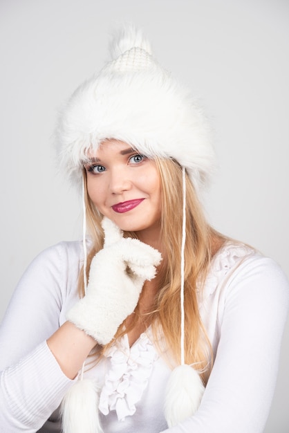 Photo gratuite belle femme en tenue d'hiver debout sur un mur gris.