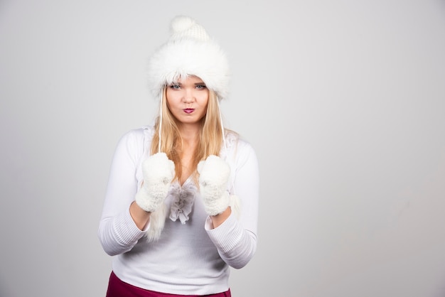 Belle femme en tenue d'hiver jouant avec un chapeau.