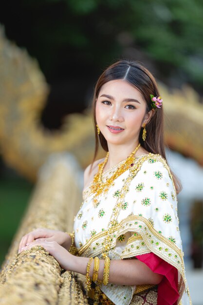 Belle femme en tenue traditionnelle thaïlandaise souriant et debout au temple