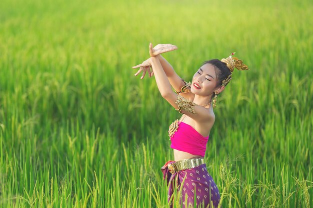 Belle femme en tenue traditionnelle thaïlandaise souriant et debout au temple