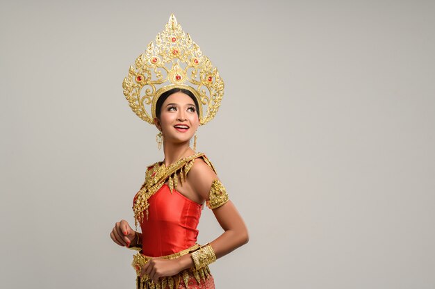 Belle femme thaïlandaise vêtue d'une robe thaïlandaise et regardant en haut