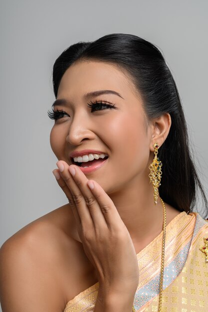 Belle femme thaïlandaise vêtue d'une robe thaïlandaise et d'un sourire heureux.