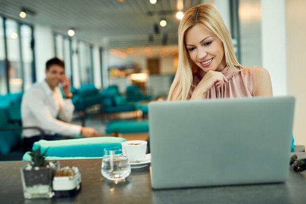 Belle femme utilisant un ordinateur portable tout en se relaxant dans un café