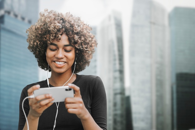 Belle femme utilisant un smartphone dans les médias remixés de la ville