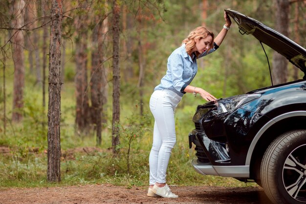 Belle femme vérifiant l'avant de la voiture