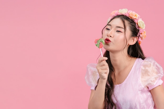 Une belle femme vêtue d'une princesse rose joue avec son bonbon sucré sur un rose.