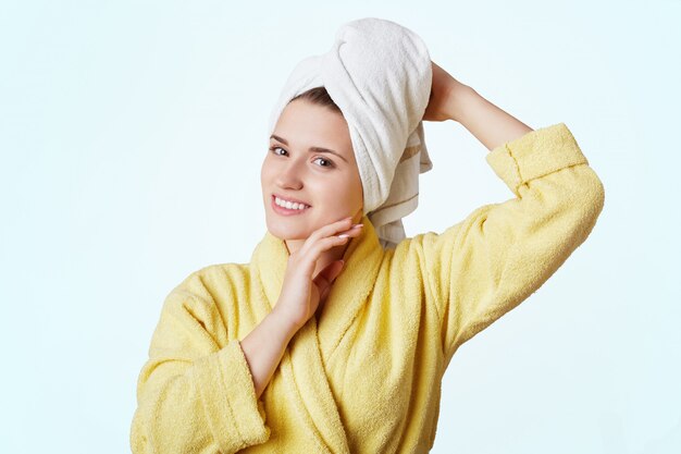 Belle femme vêtue d'une robe jaune et d'une serviette sur la tête