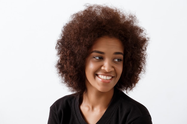 Belle fille africaine souriant sur mur lumineux.