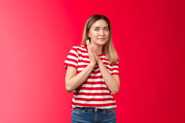 Une belle fille asiatique blonde intelligente et créative frottant les paumes ensemble sournoise et rusée ont des perf...