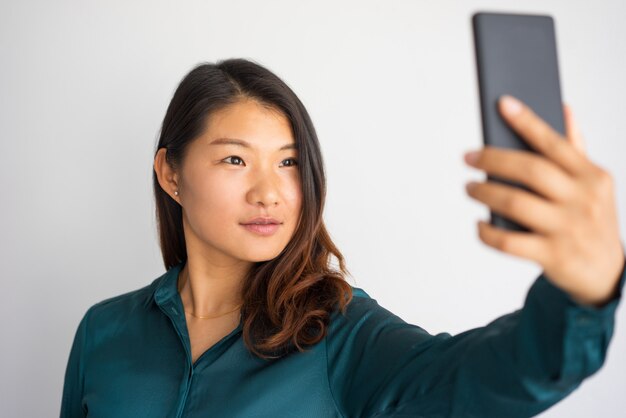 Belle fille asiatique prenant autoportrait pour le profil de médias sociaux.